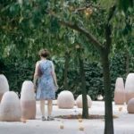 Visitors among terracotta vessels on Aquifère’s travertine platform beneath orange trees