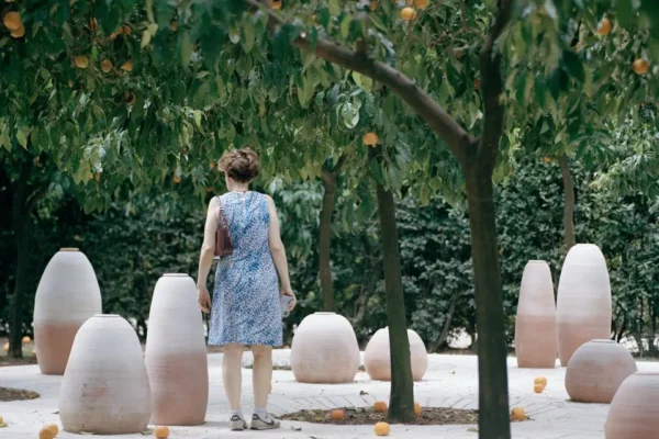 Visitors among terracotta vessels on Aquifère’s travertine platform beneath orange trees