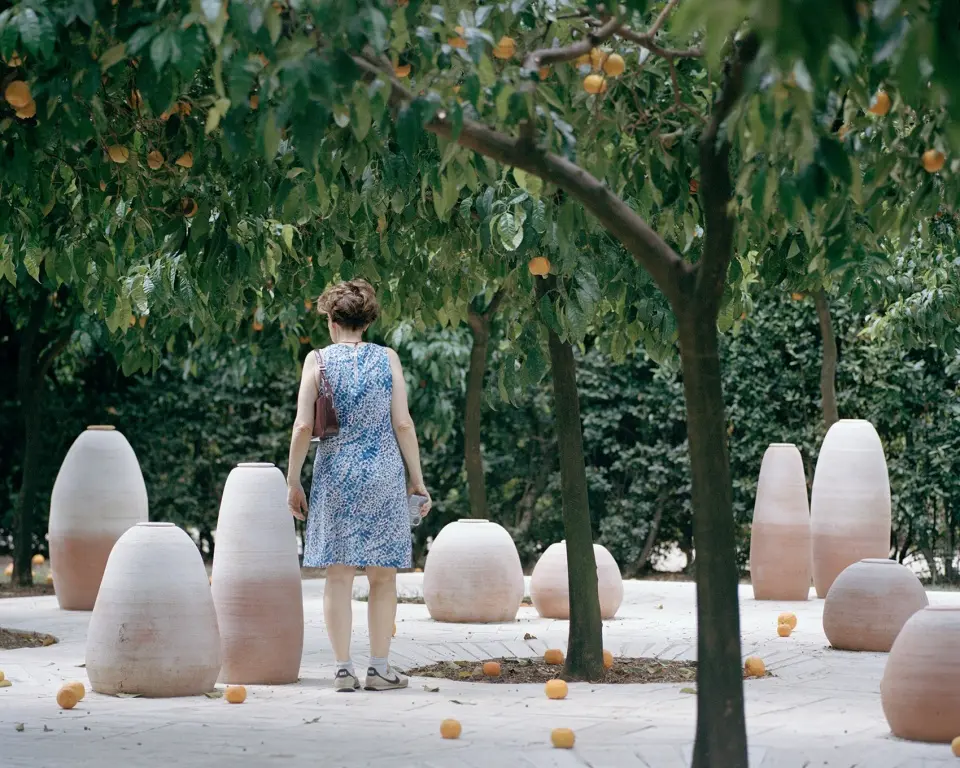Visitors among terracotta vessels on Aquifère’s travertine platform beneath orange trees