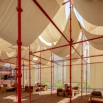 Red scaffold canopy and tent fabric over the gravel courtyard at BAG Café in Riyadh, photographed by Dua Photography Studio