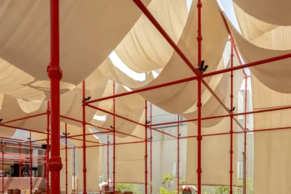 Red scaffold canopy and tent fabric over the gravel courtyard at BAG Café in Riyadh, photographed by Dua Photography Studio
