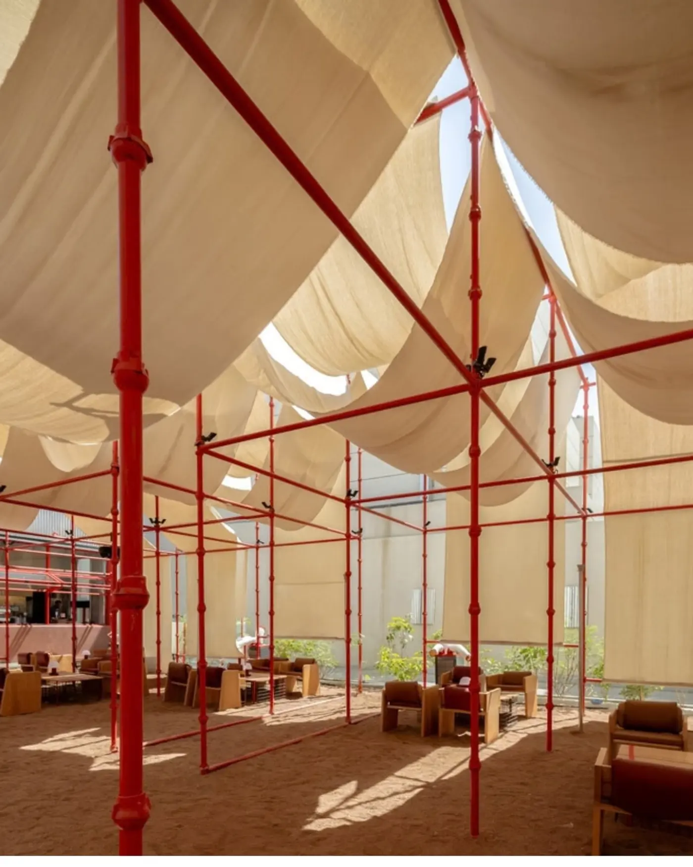 Red scaffold canopy and tent fabric over the gravel courtyard at BAG Café in Riyadh, photographed by Dua Photography Studio