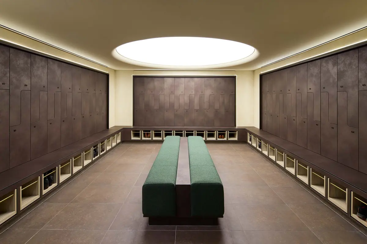 Barangaroo Wellness changing room with dark lockers, green bench and luminous circular ceiling