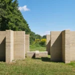 Rammed-earth columns forming open passages in a grassy clearing at Art Omi