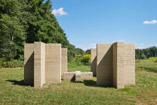 Rammed-earth columns forming open passages in a grassy clearing at Art Omi