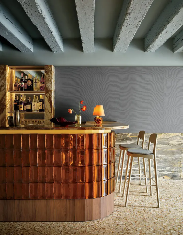 Amber glass-block cocktail bar beneath exposed ceiling beams