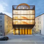 Kinderoase daycare centre by Kéré Architecture illuminated at dusk in Munich