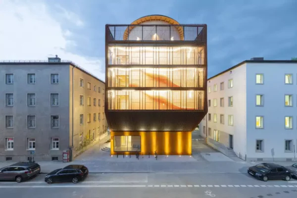 Kinderoase daycare centre by Kéré Architecture illuminated at dusk in Munich