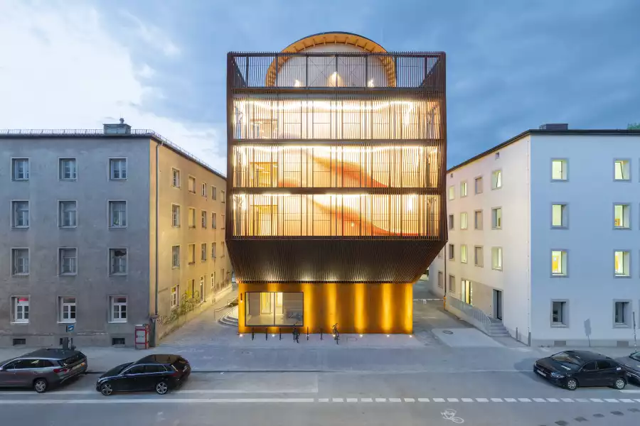 Kinderoase daycare centre by Kéré Architecture illuminated at dusk in Munich