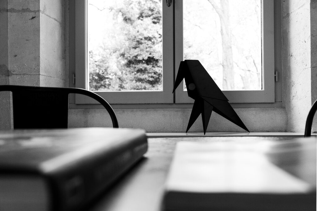Black origami-like raven sculpture on a window ledge