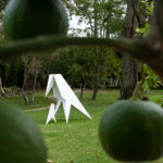 White angular raven sculpture in a garden, from Loïc Casanova’s Origami series