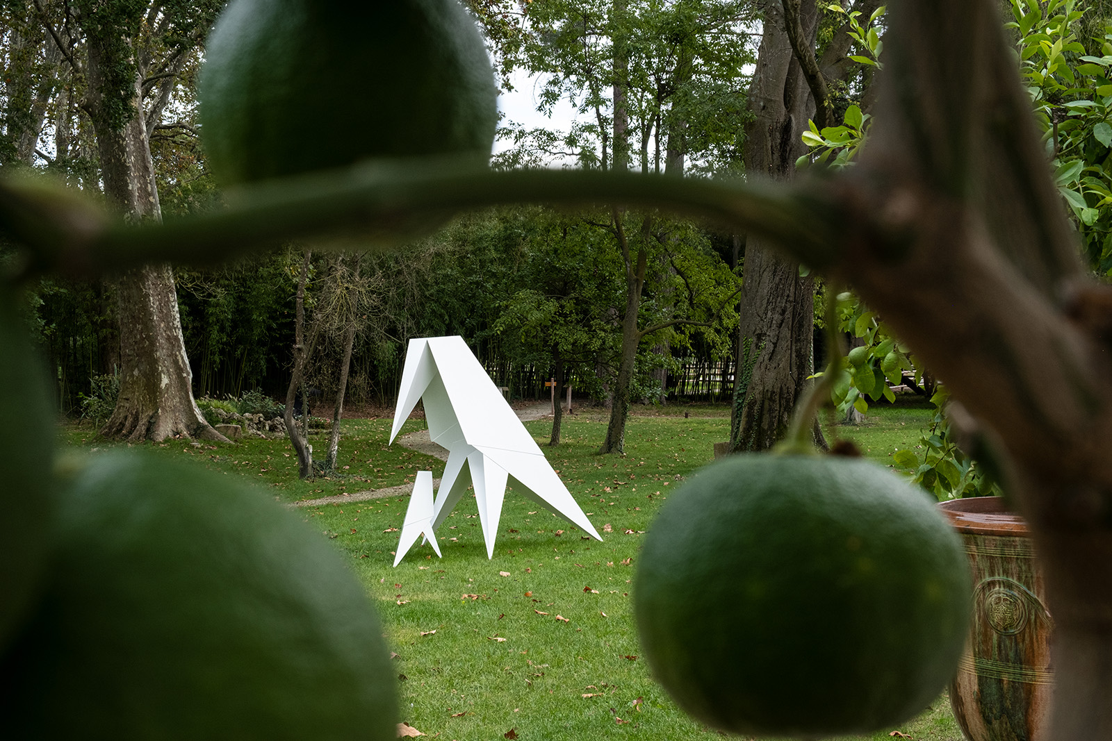 White angular raven sculpture in a garden, from Loïc Casanova’s Origami series