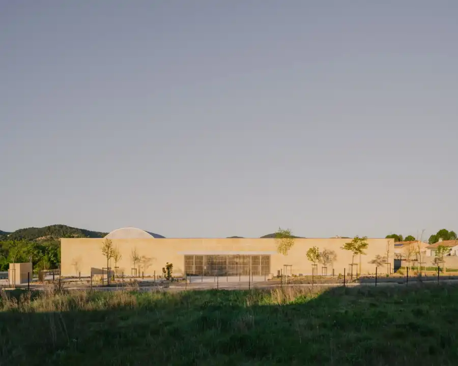Low stone enclosure and sculptural roof volumes at Tectoniques’ cultural centre