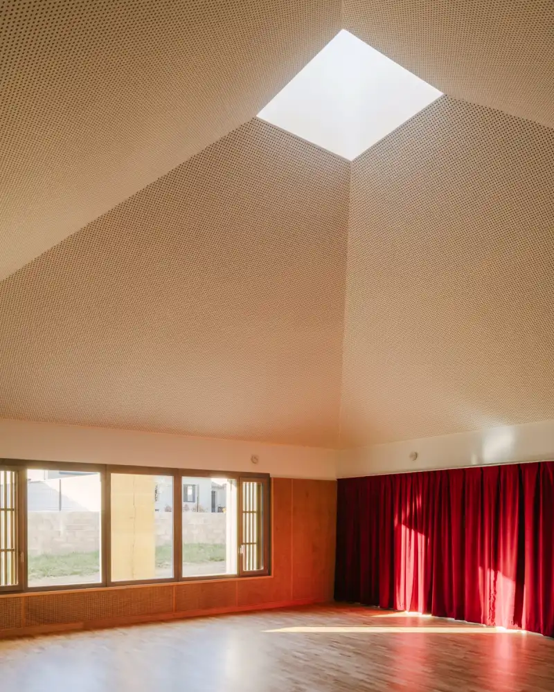 Timber-lined dance studio with a faceted ceiling and central skylight